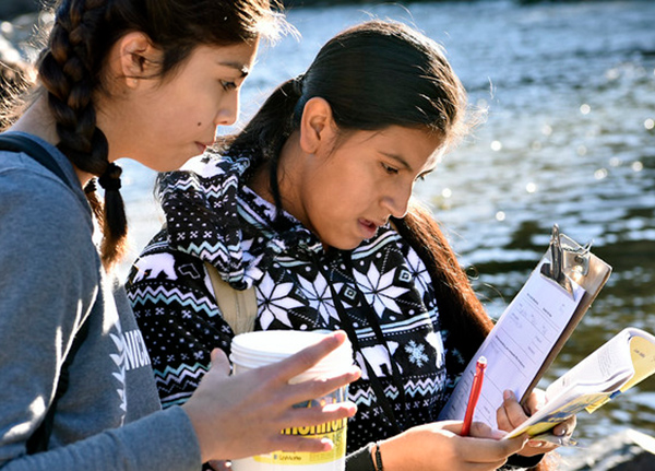 Two young women looking at clipboard with paperwork