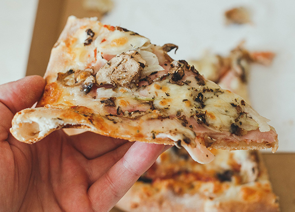 Person holds a piece of pizza